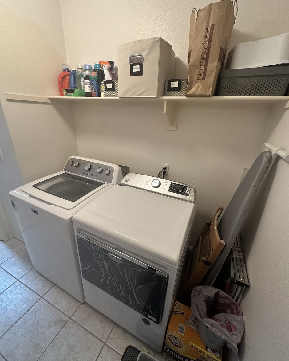 The same laundry closet from the same doorway after: clear machines and labeled bins on the shelf