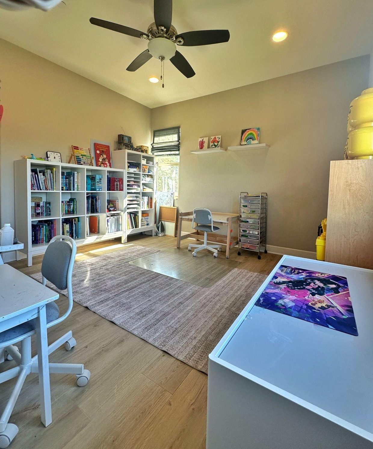The same playroom after: books in the cube shelf, clear rug, a desk ready to sit at