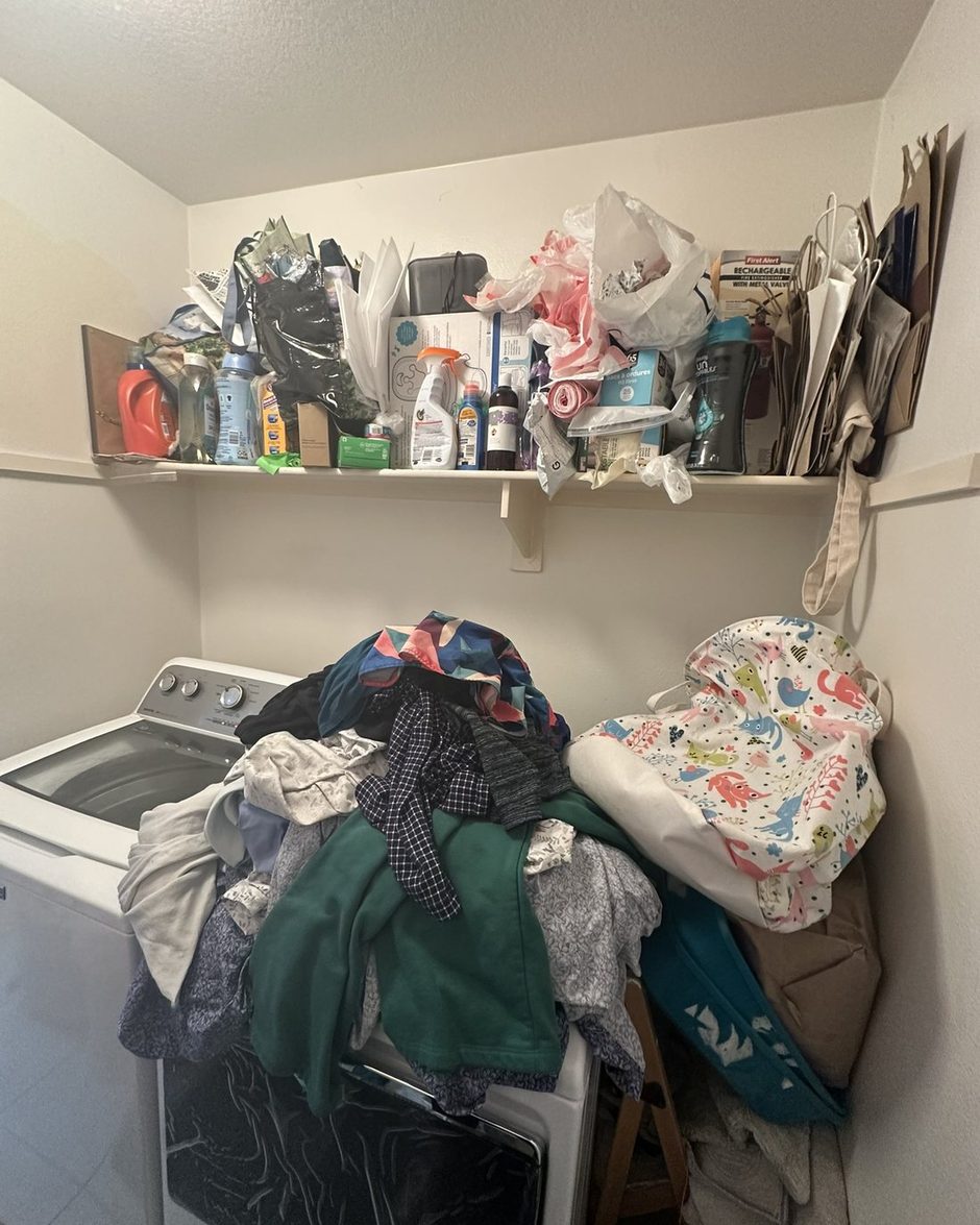 The laundry closet before: clothes piled on the machines and a crowded shelf